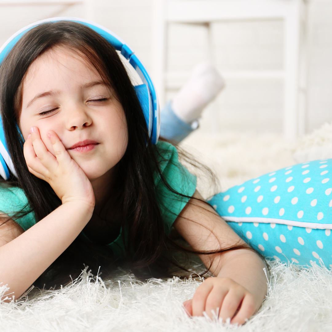 child with headphones next to blue pillow